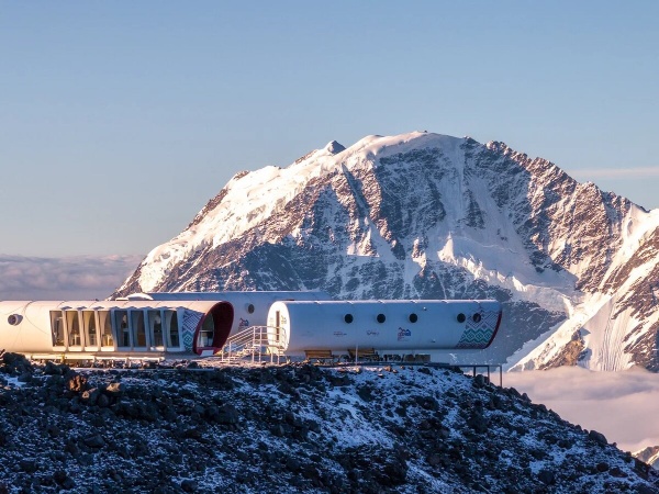 Самый высокогорный отель на Эльбрусе будет работать под брендом Космос.

Ведущий гостиничный оператор России Сosmos Hotel Group и институт развития Кавказ.РФ подписали соглашение по совместному развитию гостиничного сервиса для альпинистов на курорте «Эльбрус» в Кабардино-Балкарии. Первым этапом сотрудничества стал переход действующего высокогорного отеля-приюта Leaprus на высоте 3 912 метров над уровнем моря под бренд и франшизу Cosmos, что гарантирует работу по стандартам сервиса и качества федерального оператора.

С началом нового альпинистского сезона 2026, который традиционного проходит с апреля по сентябрь, эко-отель LeapRus откроется под названием Cosmos Elbrus Leaprus Camp. Его уже можно забронировать на сайте Cosmos Hotel Group на период проживания с апреля по сентябрь 2026 года. Кроме того, объект появится в программе лояльности Cosmos Stars, что позволит участникам программы оплачивать проживание накопленными баллами. 

Эко-отель был построен в 2013 году и находится на высоте 3 912 метров над уровнем моря рядом со станцией канатной дороги «Гарабаши» курорта «Эльбрус», ближайший населенный пункт – село Терскол. Служба приема и размещения отеля располагается на поляне Азау, рядом с кассами на канатную дорогу. 

Объект стал центром акклиматизации и отдыха для профессиональных альпинистов и тех, кто выбирает активный или экологический туризм на вершине Эльбрус. Для комфортного размещения отель предлагает суммарно 34 спальных места в модулях с системой отопления, горячей водой и душем, гардеробной зоной и большим панорамным окном с видом на вершины Кавказских гор. На территории отеля работает wi-fi, есть кафе-столовая и помещение для сушки экипировки и снаряжения. В ночное время территория отеля освещается и оборудована системой сигнальных огней. 

«Для нас – это знаковый проект и первый самый высокогорный отель в Европе под нашим брендом. Для нас важно создавать и развивать качественный гостиничный сервис для самых разных категорий гостей, и экстремальные туристы и альпинисты не исключение. Уверен, что совместный опыт и экспертиза Cosmos Hotel Group и института развития Кавказ.рф создадут комфортный отдых для тех, кто покоряет вершину Эльбрус со всего мира», – отметил президент Cosmos Hotel Group Александр Биба. 

«Все проекты, которые связаны с высокогорьем Эльбруса, по умолчанию становятся "самыми" в стране: в первую очередь самыми сложными технически и логистически. Продолжаем сейчас строить инфраструктуру для восхождений: возводим альпгородок на 68 мест и готовимся выйти на стройку "Приюта одиннадцати", поэтому опыт построения высокогорного отельного сервиса в ближайшие годы будет как никогда востребован. Кроме того, работа на горе – это трансформирующий опыт сродни восхождениям: кто справится с вызовами здесь, сможет достичь любых высот на равнине. Поэтому уверен, что опыт работы с Leaprus так или иначе повлияет на работу Сosmos Hotel Group в целом», – сказал генеральный директор Кавказ.РФ Андрей Юмшанов. 

Ранее, на Кавказском инвестиционном форуме Сosmos Hotel Group и институт развития Кавказ.РФ подписали соглашение о совместном развитии туризма и подготовке кадров для индустрии гостеприимства в регионах Северного Кавказа. 

Эльбрус – легендарный и самый высокогорный курорт страны, который делает доступной гостям высоту 3847 метров над уровнем моря. Работает с 70-х годов прошлого века и неизменно остается одним из главных центров горнолыжного отдыха, спорта, альпинизма в стране. Модернизация курорта идет под управлением Кавказ.РФ:  в новом сезоне расширена зона катания и запущена система оснежения, которая позволит продлить и без того самый продолжительный горнолыжный сезон в России – с ноября по июль. 

LeapRus – один из самых высокогорных отелей мира, современная акклиматизационная база для альпинистов, которая отличается необычным для высоты 3912 метров комфортом: есть электричество, горячая вода, интернет, сушильные камеры. В кают-компании можно приготовить еду самостоятельно или питаться в формате шведского стола. Два жилых модуля рассчитаны на 24 гостя. 

Гостиница построена итальянской компанией Leapfactory по заказу Северо-Кавказского горного клуба. Технология рекуперации тепла, светодиодное освещение, теплоизоляционные и антибактериальные свойства материалов – всё служит максимальной автономности, энергоэффективности и экологичности комплекса. Разборные элементы капсул, которые монтировали на фундамент с помощью вертолетов, обеспечивают сейсмоустойчивость всех конструкций. 

Архитектура гостиничного комплекса – обтекаемый дизайн, иллюминаторы, панорамное остекление, геометричность – отсылает к стилистике ретрофутуризма и модернизму середины века. 

Cosmos Hotel Group – ведущий федеральный гостиничный оператор России, бренд которого создан в 2018 году. В портфель компании входит 44 отеля исключительно категорий от 3* (городские отели) до 5* (отели премиум-класса, в том числе и курортные комплексы) в 28 городах России. Компания осуществляет операционное управление активами с номерным фондом более 11,5 тыс. единиц.