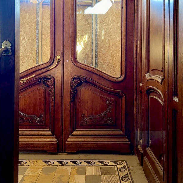 Дом Бака в Санкт-Петербурге вернул себе дореволюционные двери.

В доме 24 по Кирочной улице по инициативе и стараниями самих жильцов восстановлены исторические двери в парадных подъездах. 

История с восстановлением началась в 2017 году, когда жильцам дома стало известно, что несколько дверей из парадных оказались в кафе «Рубинштейн» — там их использовали для оформления интерьеров. Из доходного дома, построенного в начале XX века архитектором Юлианом Баком, они пропали еще в конце 1990-х: коммунальные службы тогда заменили деревянные двери на железные. 

К моменту, когда две пары исторических дверей нашлись, жильцы дома уже создали сообщество в соцсетях, занимавшееся проектом по возвращению зданию исторического облика.

Каждая парадная дверь — это целый комплекс объектов: две пары деревянных дверей, тамбур между ними с керамической плиткой на полу, деревянными дверями по бокам тамбура и системой его отопления. Сохранившиеся исторические двери отреставрировали, по их образцам воссоздали недостающие две пары, отреставрировали верхние застекленные фрамуги над дверями, напольное покрытие, воссоздали по имеющимся фотографиям ручки дверей.

И вот теперь, спустя почти семь лет посла начала этой эпопеи, две пары исторических и две пары воссозданных по их образцам дверей заняли в двух парадных подъездах свое изначальное место.